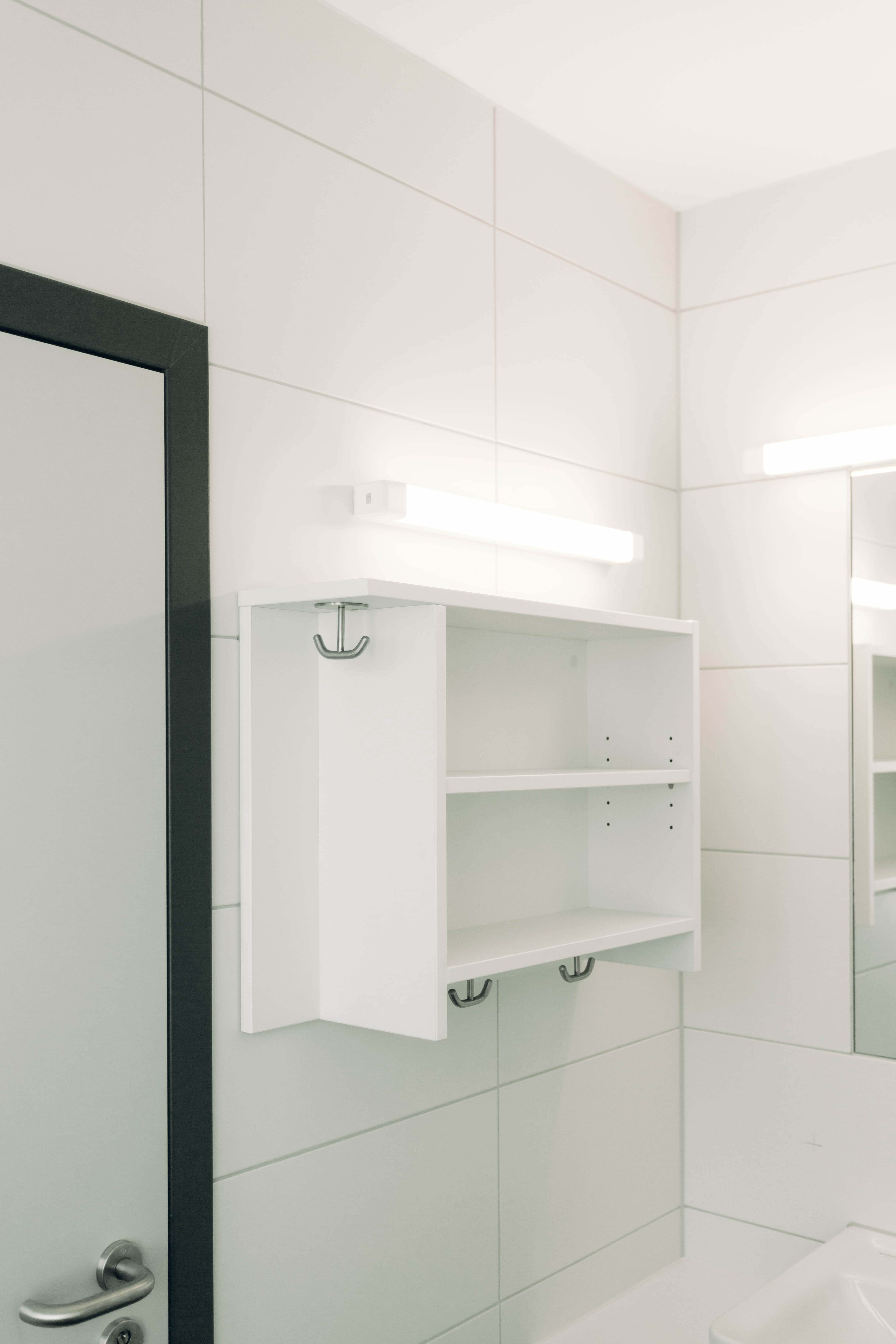 Weißes Regal in Badezimmer mit Haken und Ablageflächen